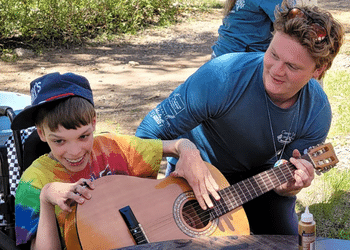 Camp Wamp camper playing guitar.