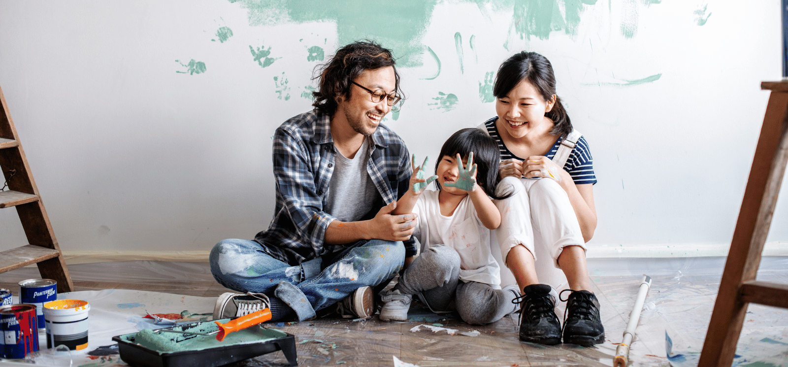 Family of three sitting on floor with paint.