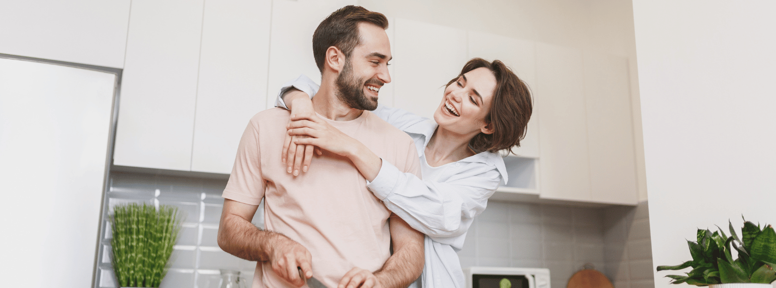 Smiling couple looking at each other and standing in the kitchen.