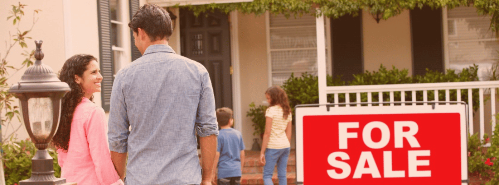 Home for sale with smiling family in the background.