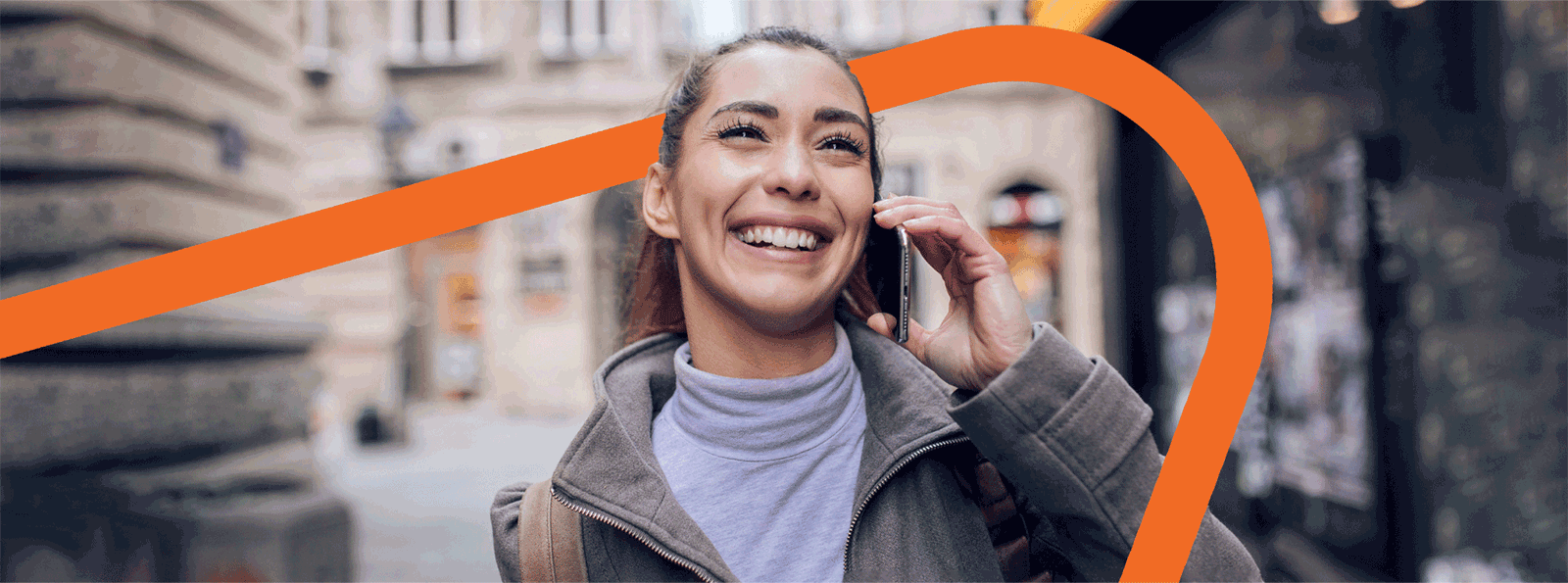 Smiling female with her cell phone held up next to her ear.