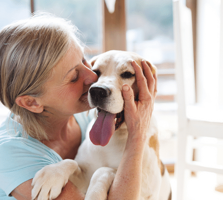 Woman smiling while holding a dog.