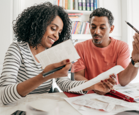 Smiling couple sitting and reading over paperwork.