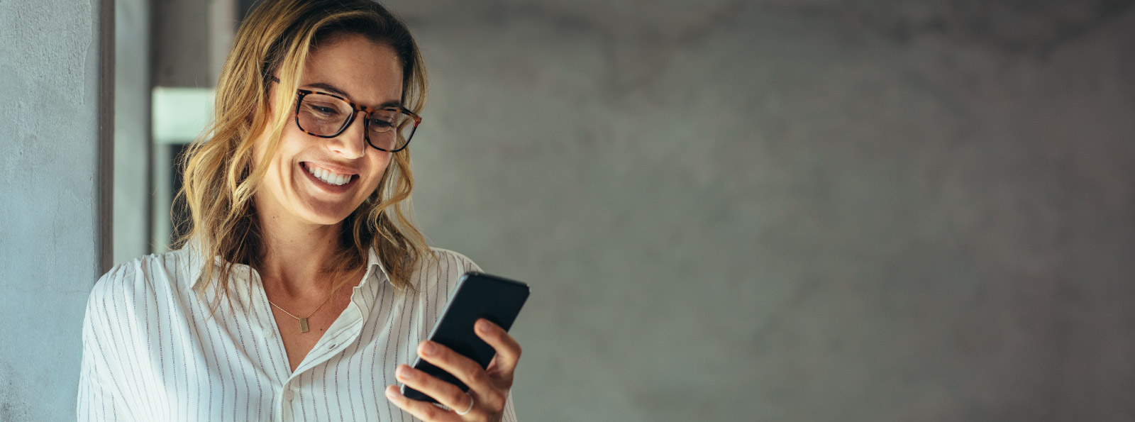 A woman smiling and holding a smartphone.