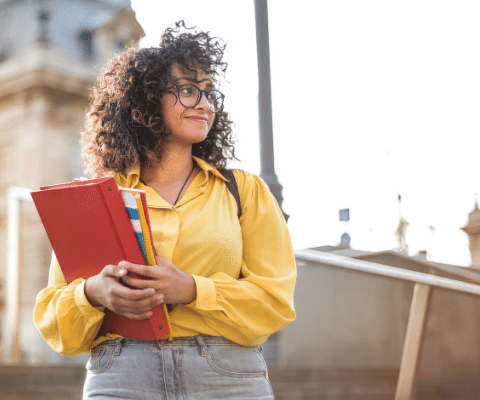 Woman smiling outside and holding notebooks