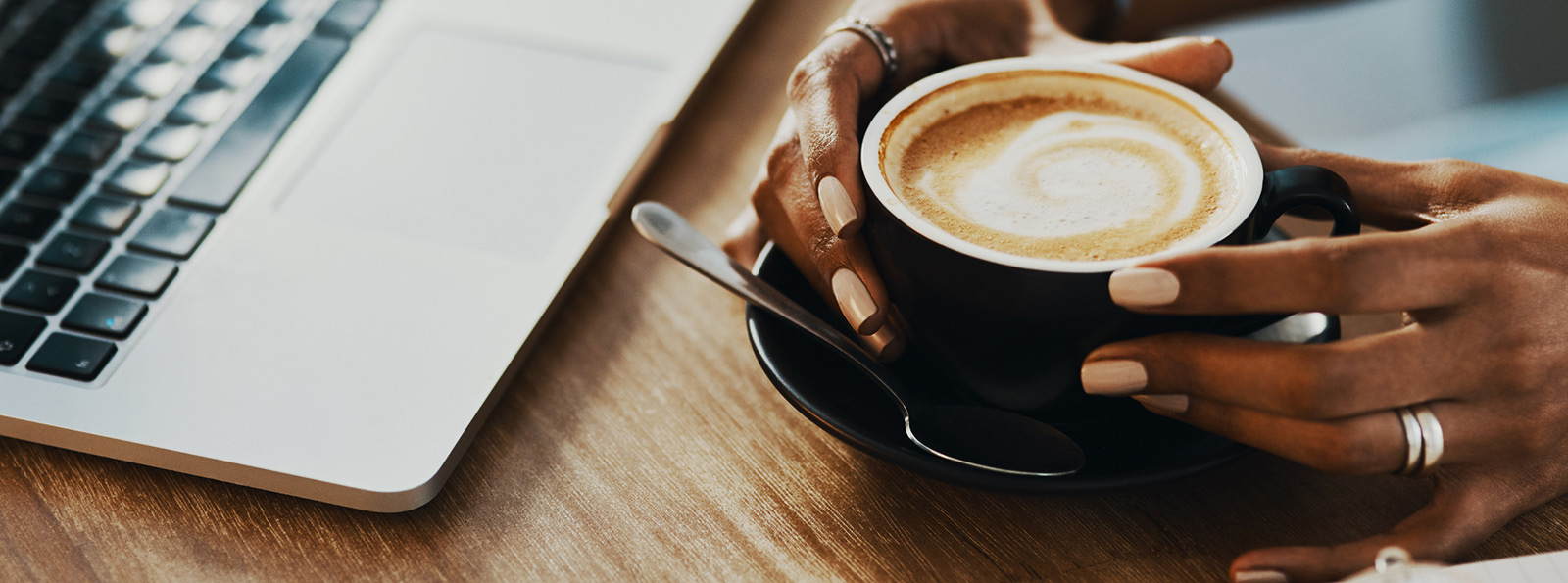 a cup of coffee on a desk next to a laptop computer