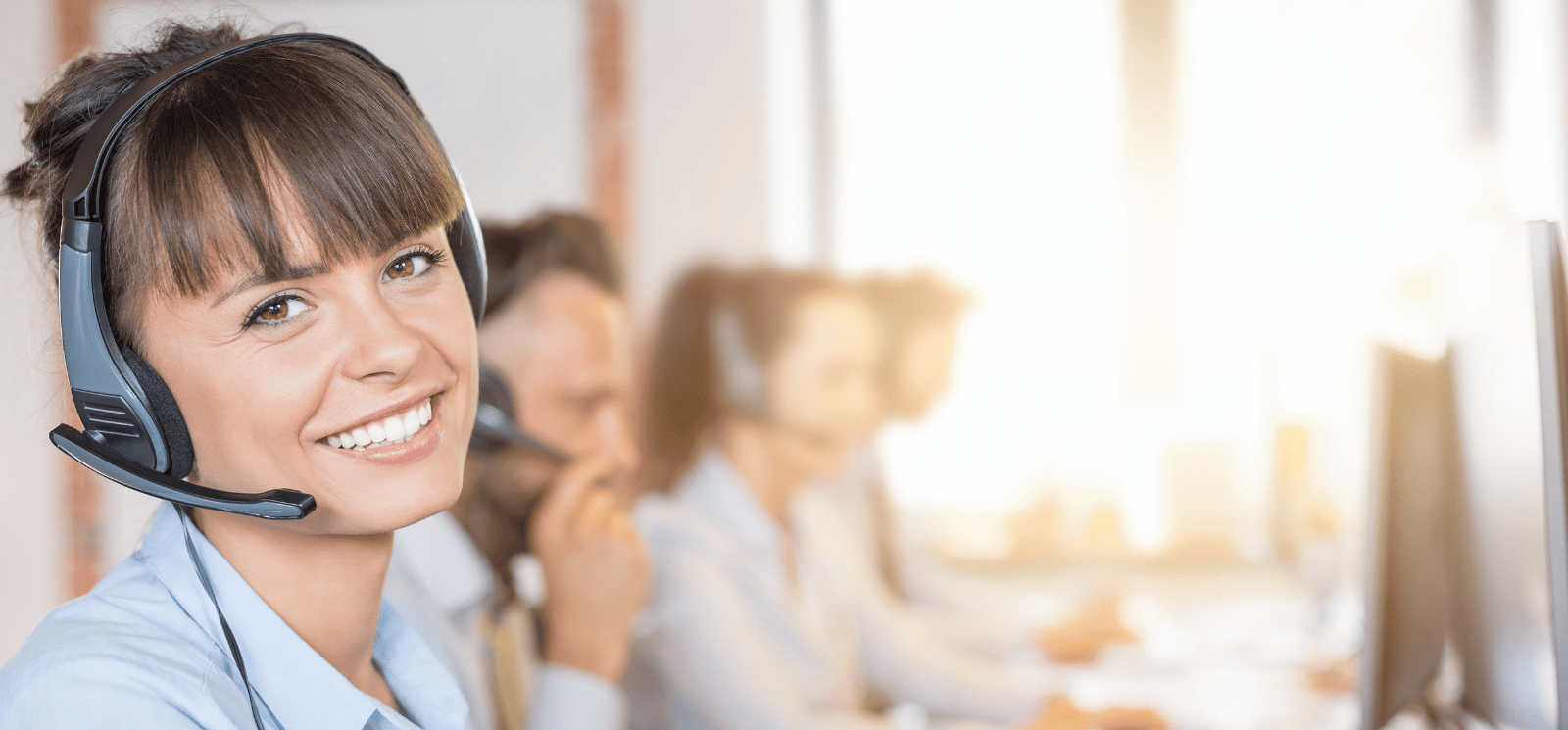 Smiling woman wearing a headset in a Contact Center.