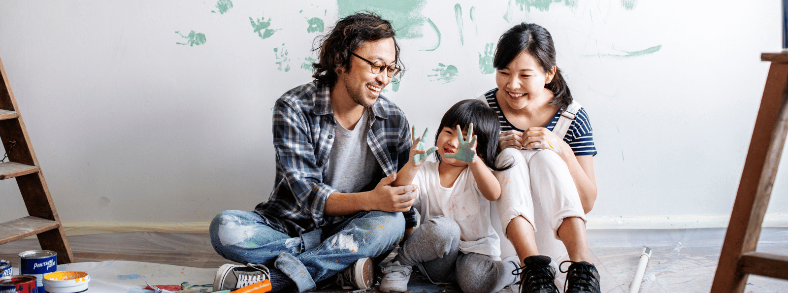 Family of three sitting on floor with paint.