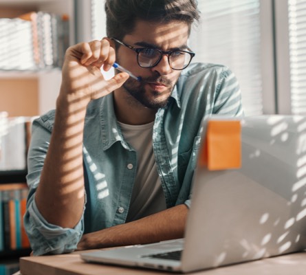 A man with a puzzled look starting at a laptop.