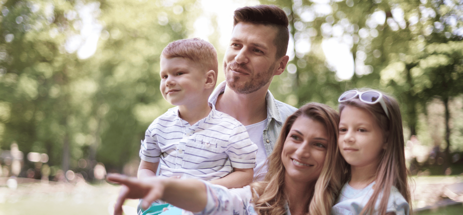 Family of four standing outside and smiling.