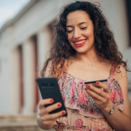 a woman holding her mobile device with a credit/debit card