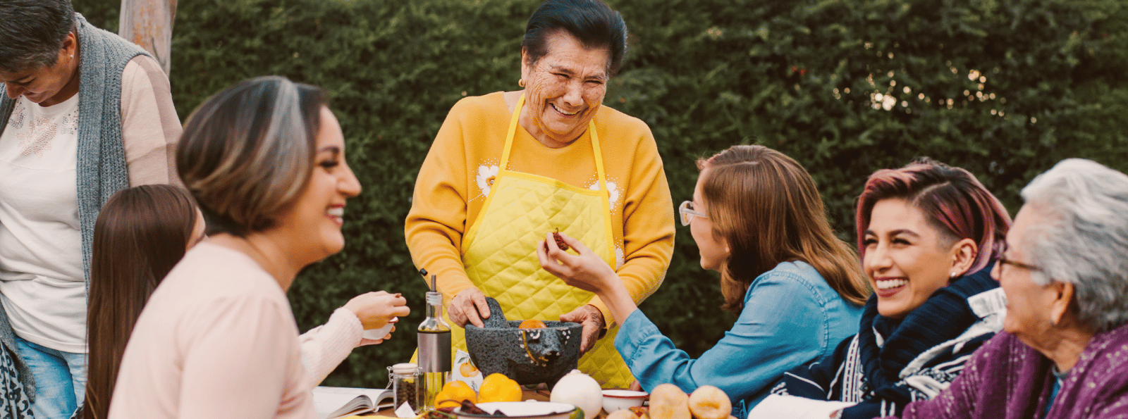 Smiling family sitting at a table outside.