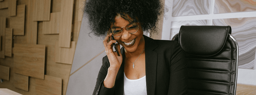 Smiling businesswoman sitting and smiling while on her cellphone.