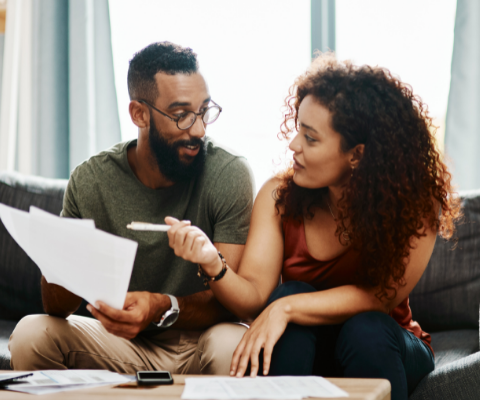 Couple on couch reviewing financial paperwork