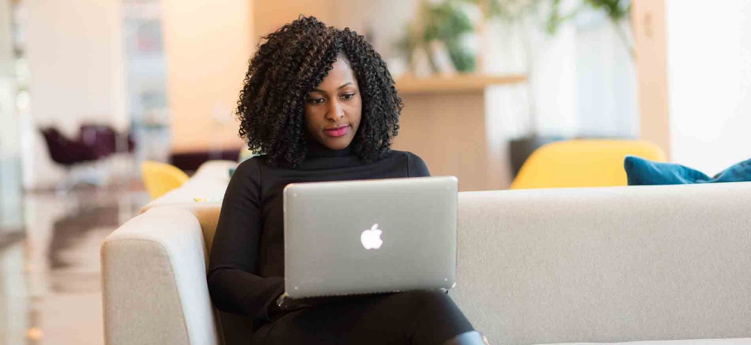 a woman viewing her laptop on her couch