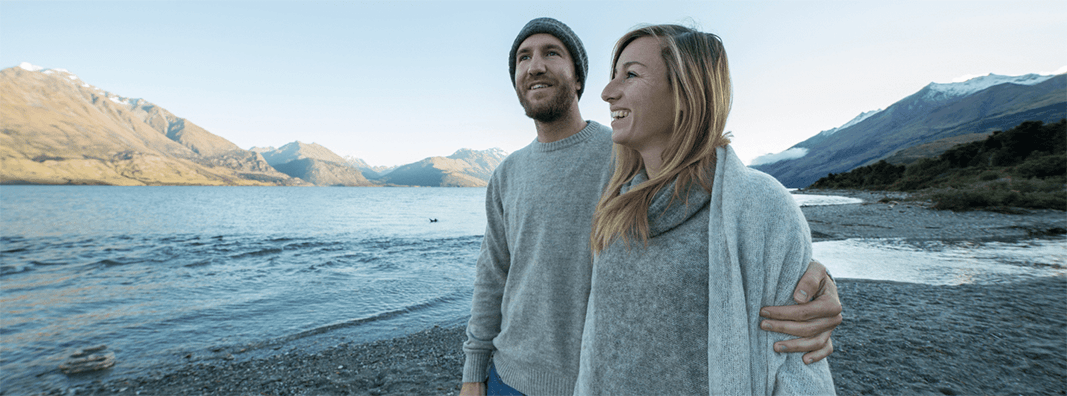 Couple walking along a lake's shoreline.