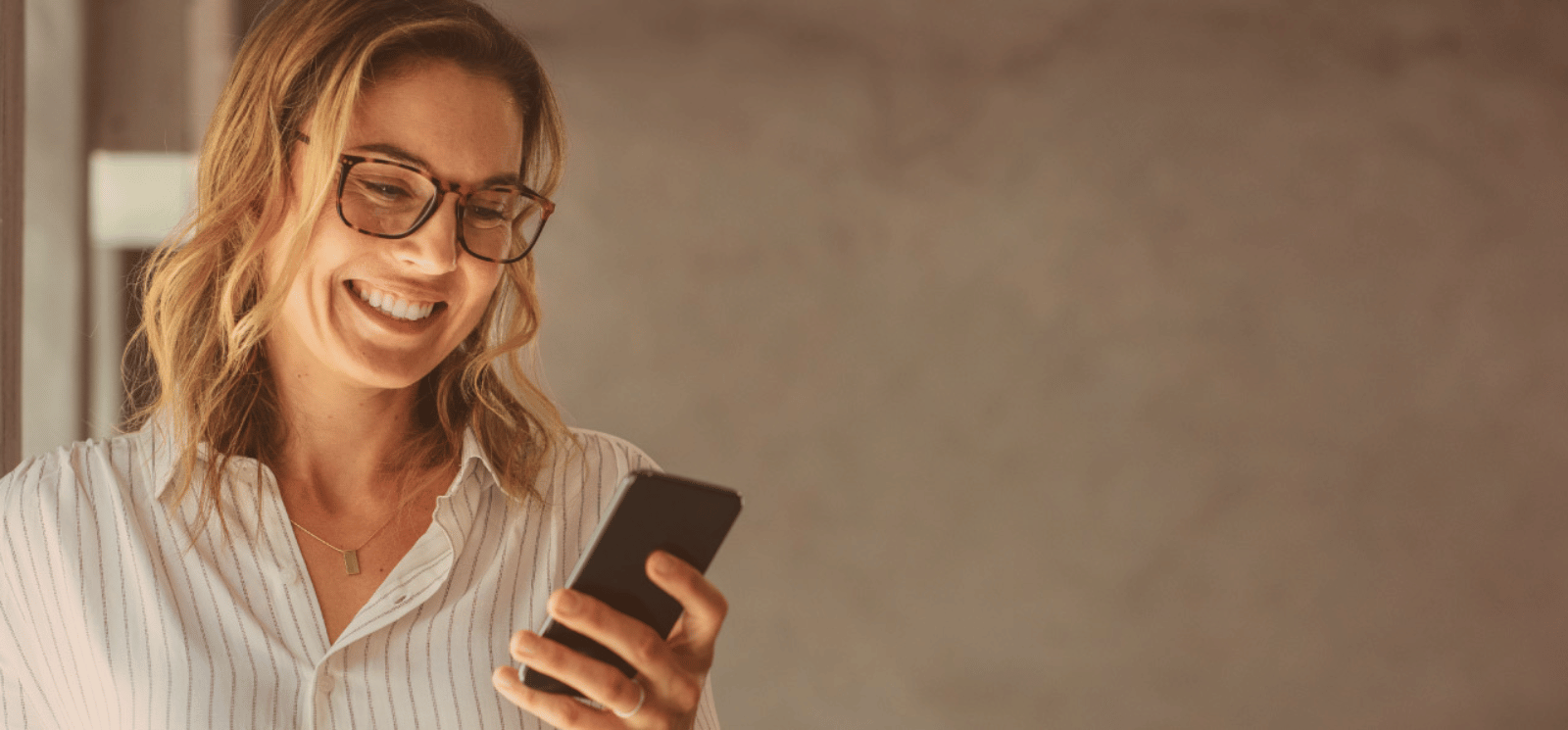 Smiling woman holding a cell phone.