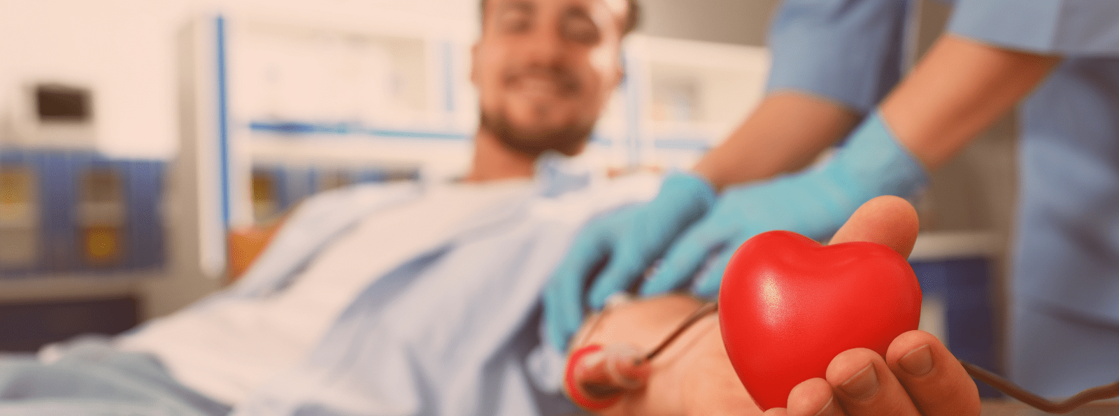 Blood donor smiling and holding a heart-shaped squeeze ball in his hand.