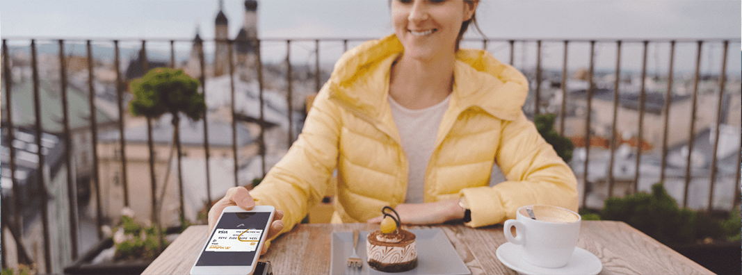 Woman sitting at a table and paying with her mobile wallet