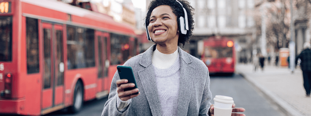 Woman wearing headphones and holding a cell phone.