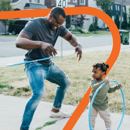 A dad playing hula hoop with his young daughter.
