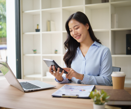 Woman smiling at a desk with a calculator and financial planning sheet.