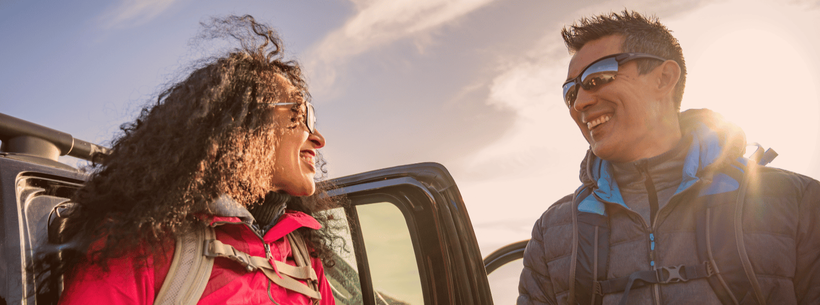 Smiling couple standing next to car.