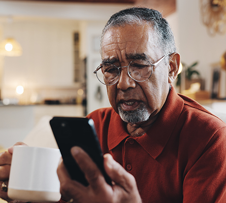 Man holding a cell phone and a coffee mug.