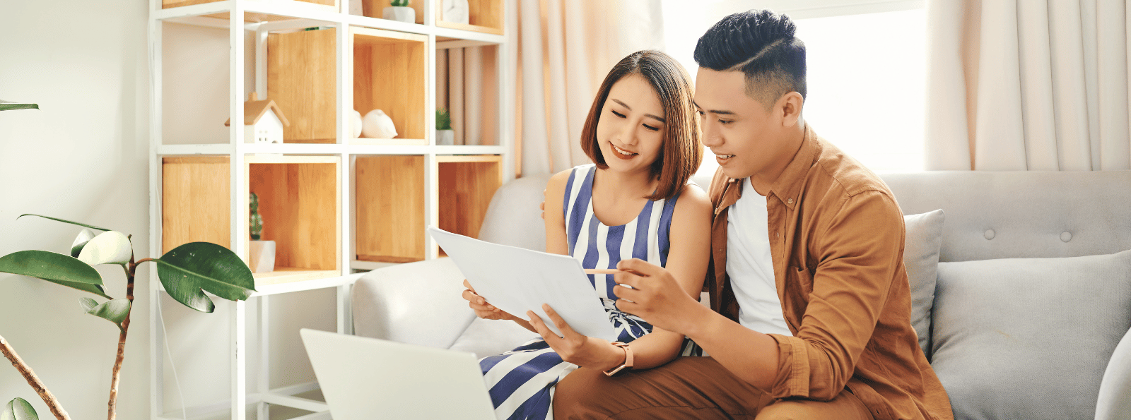 Man and woman sitting on a sofa looking at paperwork.