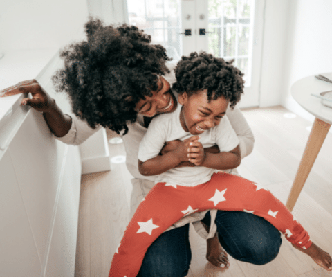 Mom and child laughing together in a room in front of french doors