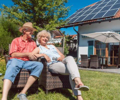 Couple sitting outside in front of solar panels on a roof