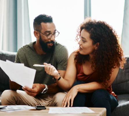 Couple sitting on couch reviewing paperwork.