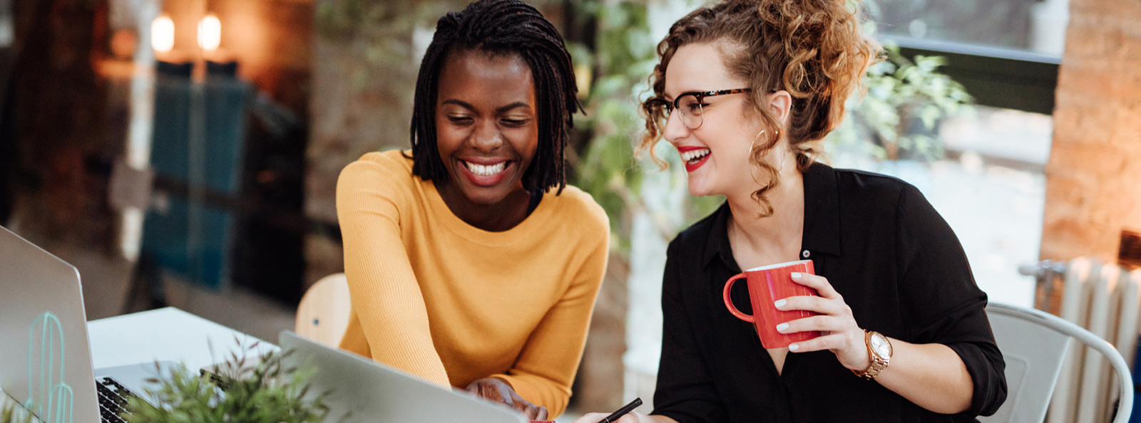 Two women in an office looking at a laptop.