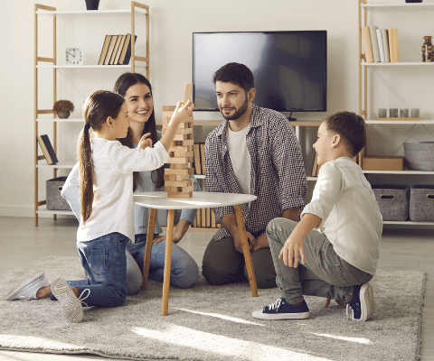 Family of four in front of TV playing a building blocks game.