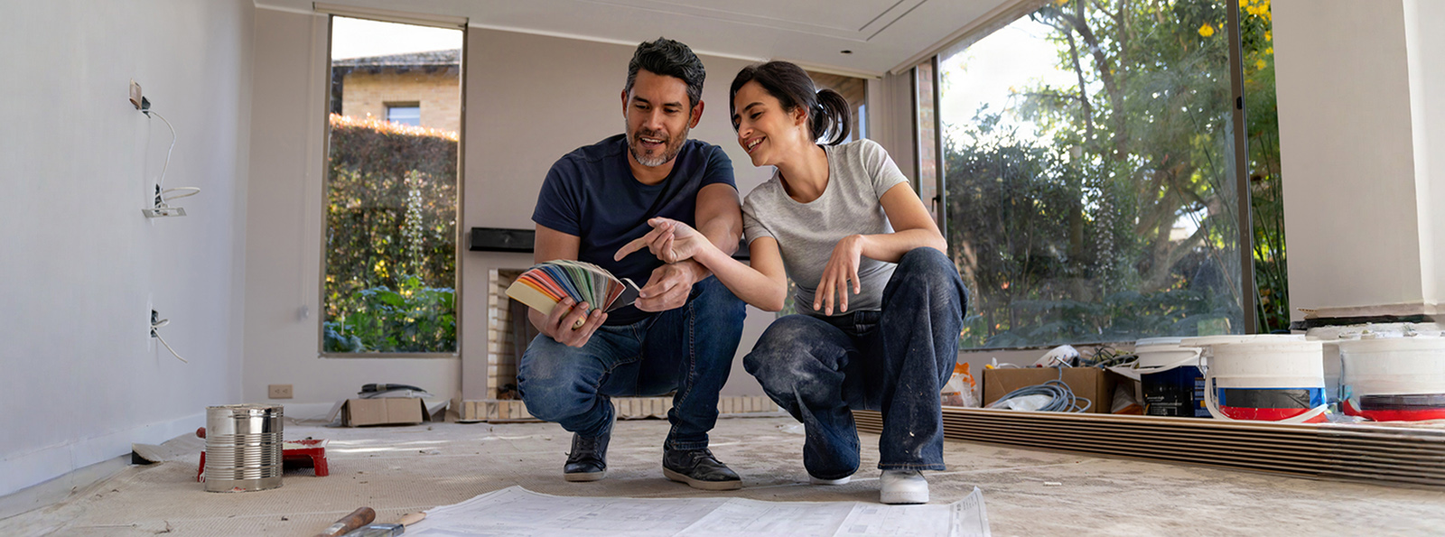 Smiling couple in a living space holding paint color samples.