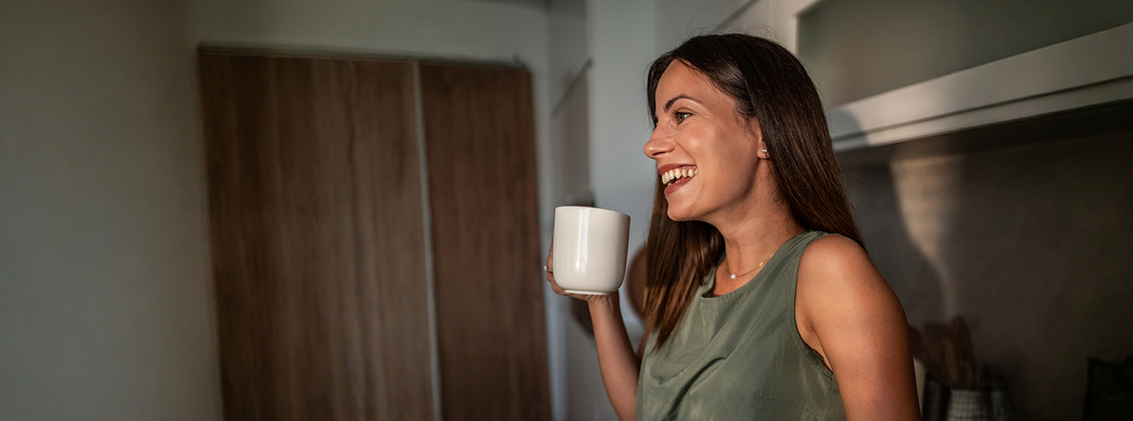 Smiling woman holding a coffee mug.