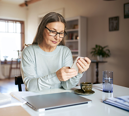 Woman holding a cell phone sitting at a table.