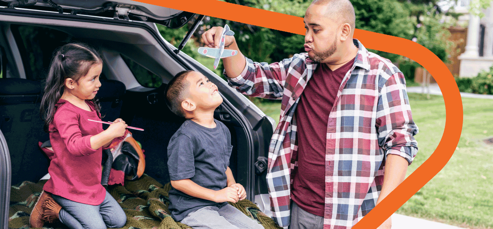 Dad and two kids sitting on tail of car.