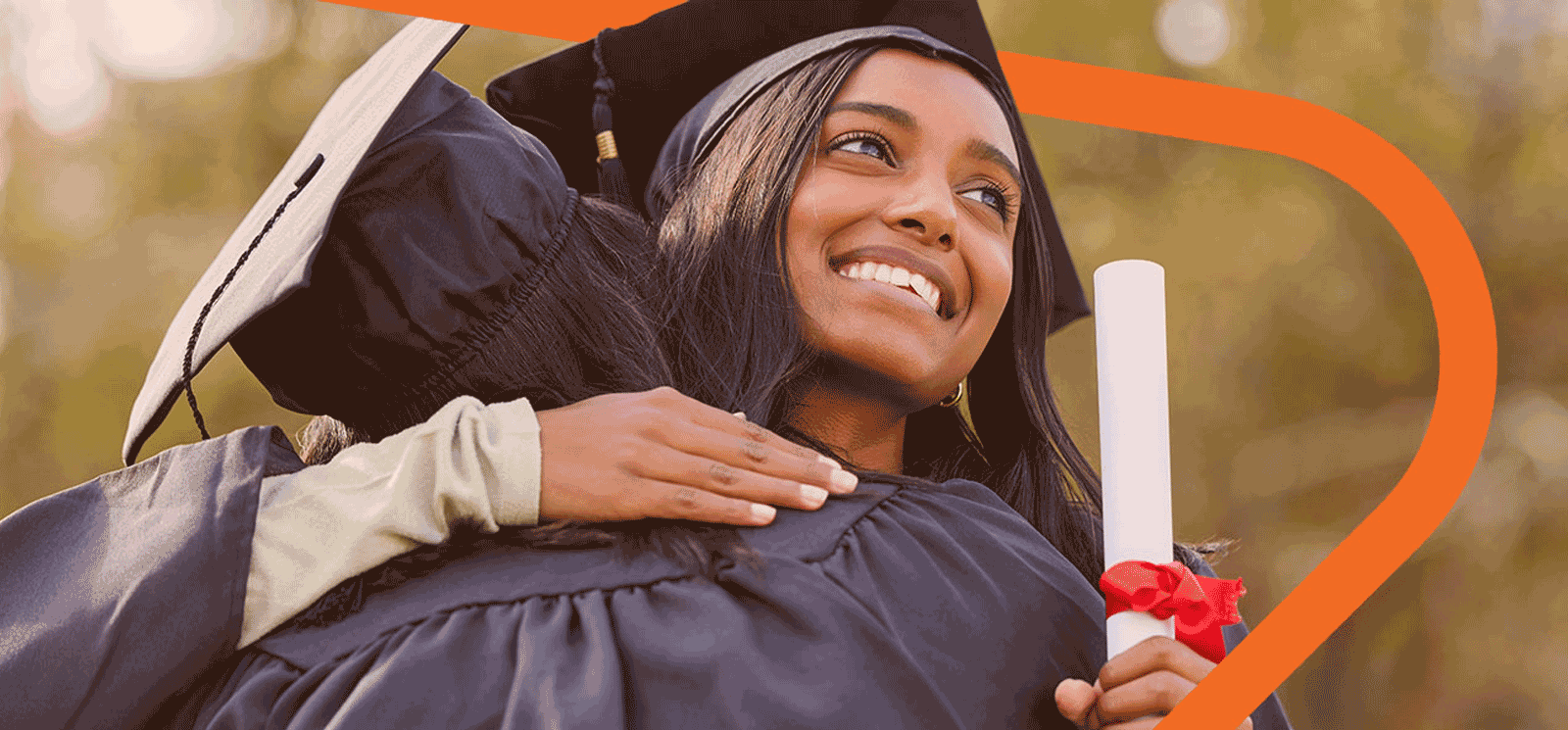 Smiling Female wearing a cap and gown and hugging another person.