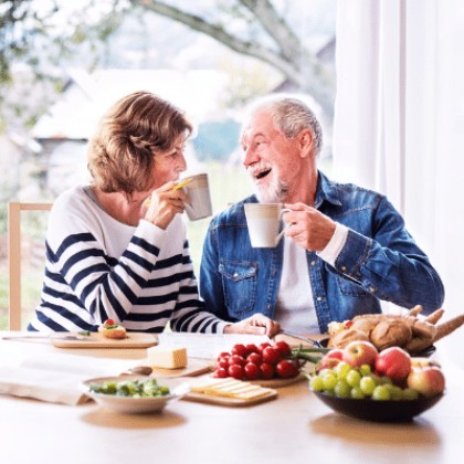 a mature couple sitting at their kitchen table drinking coffee