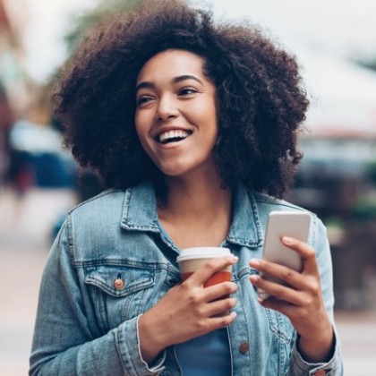 a woman holding a cup of coffee and a mobile phone