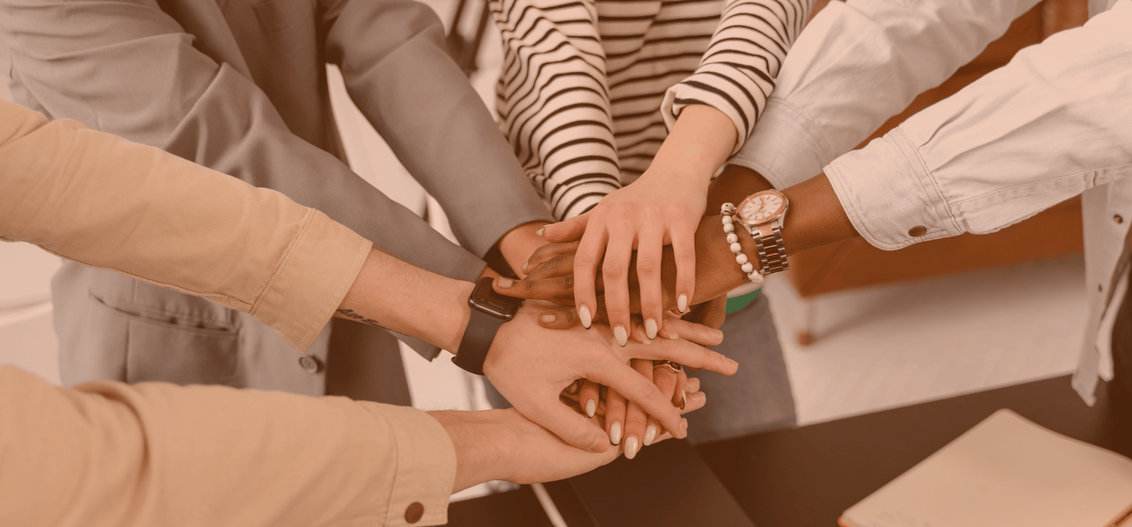 People's hands, one on top of another, forming a stack.
